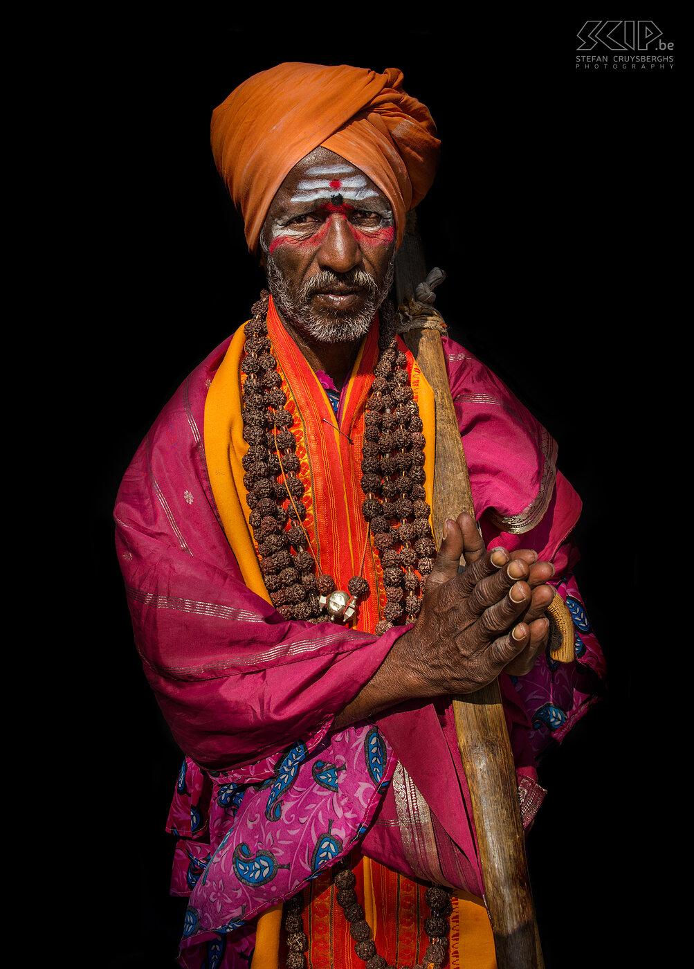 Hampi - Sadhoe In Hampi leven er ook een aantal sadhoes die donaties krijgen van de lokale bevolking en de toeristen. In het hindoeïsme is een sadhoe is een religieuze asceet of heilige man die alle materiële voorzieningen achter zich heeft laat en zich richt op het spirituele van het hindoeïsme. Dit is een van de tulband-sadhoes in Hampi. Ze dragen felgekleurde kleding en versieren hun gezicht met witte en rode verfpatronen. Stefan Cruysberghs